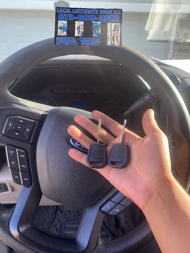 A technician from Local Locksmith Pros LLC showcasing a Car Key Replacement by holding two new keys in their palm inside a Ford vehicle.