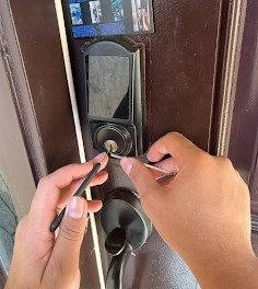 A technician from Local Locksmith Pros LLC performing Commercial Lock Repair on a black smart lock, using specialized tools to pick or service the cylinder.