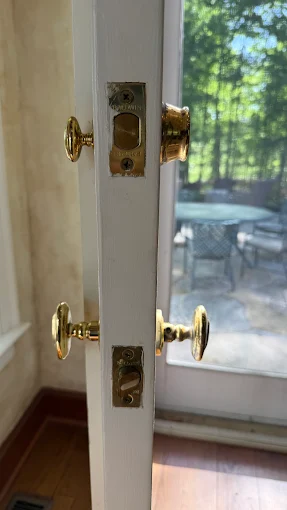 Deadbolt Installation by Local Locksmith Pros LLC, showing the side profile of a white door with a newly fitted deadbolt and a separate door handle, both with brass finishes.