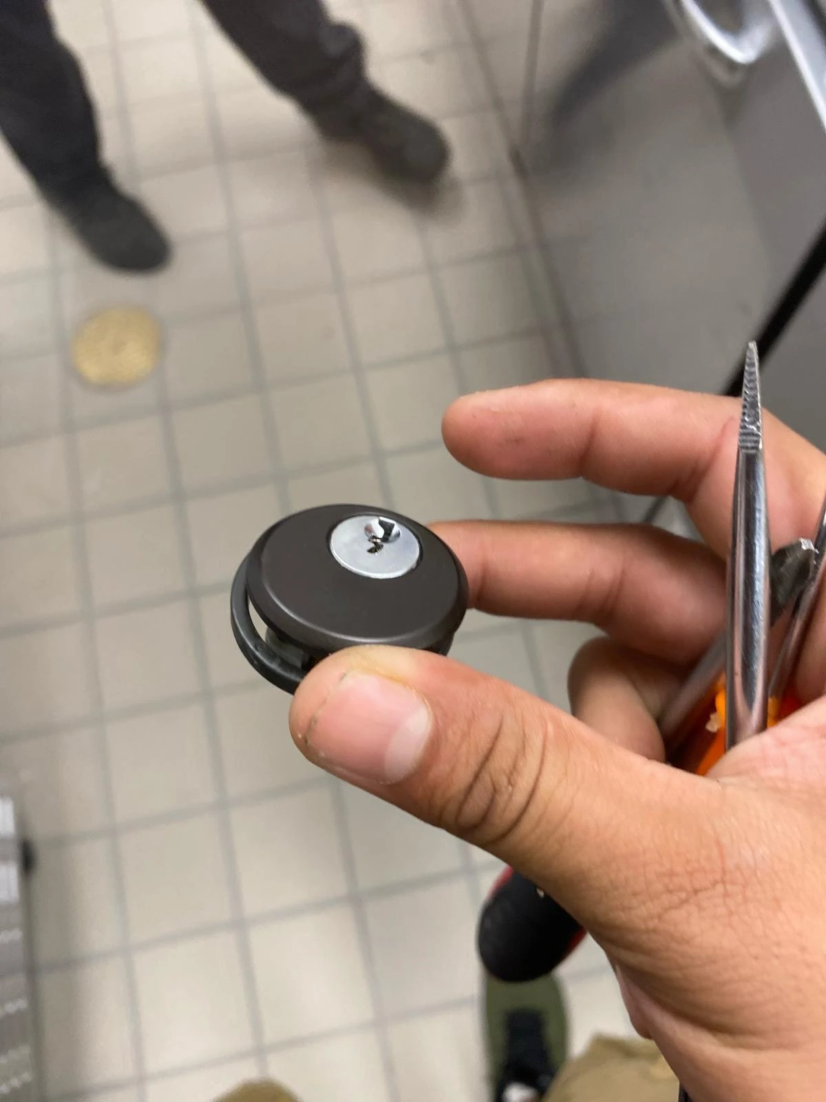 A locksmith technician from Local Locksmith Pros LLC holding a small, round residential lock cylinder, ready for a precise Residential Lock Installation.