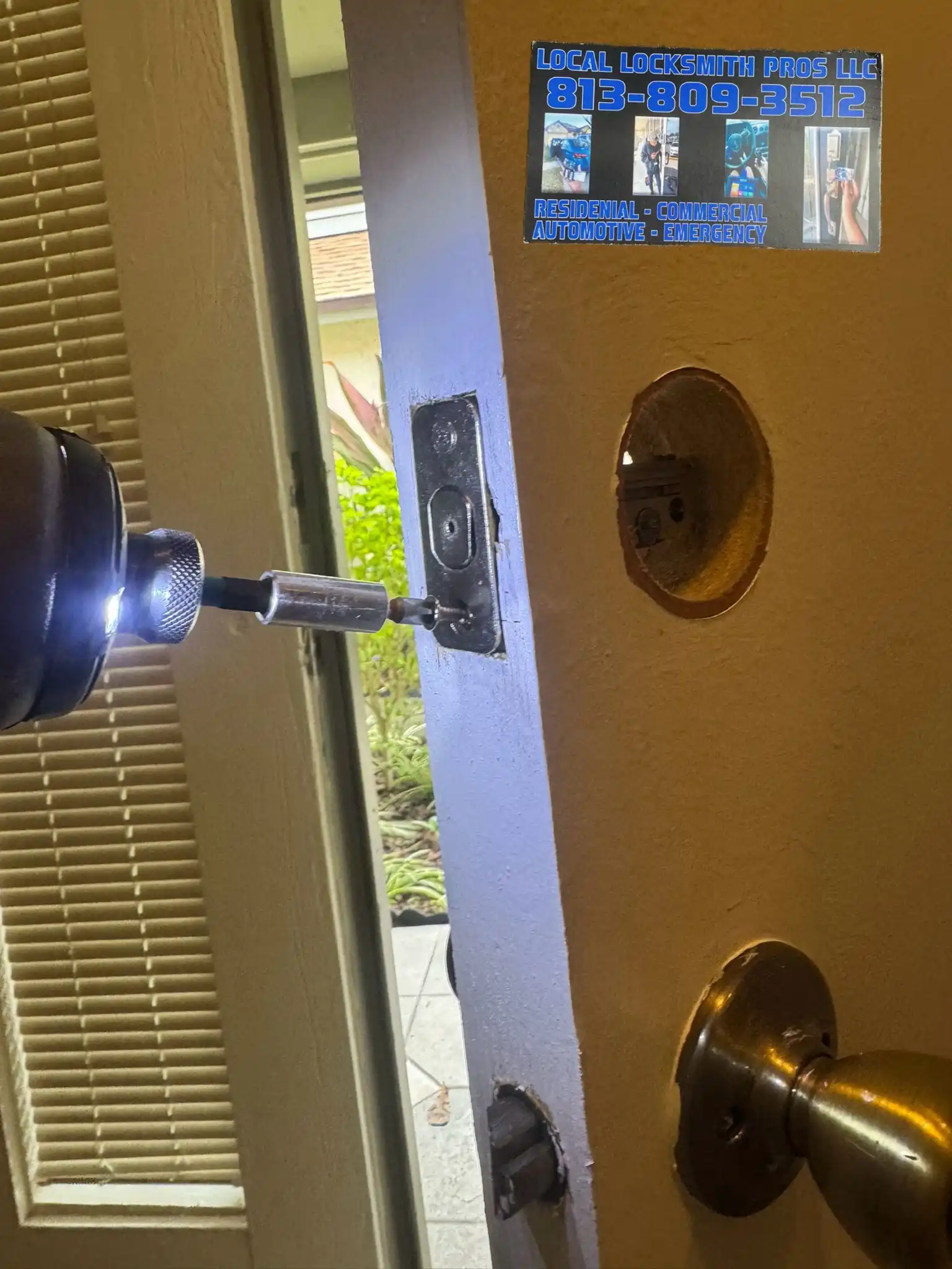 A technician from Local Locksmith Pros LLC performing a Lock Installation, using a power drill to secure the latch plate on the edge of a door.