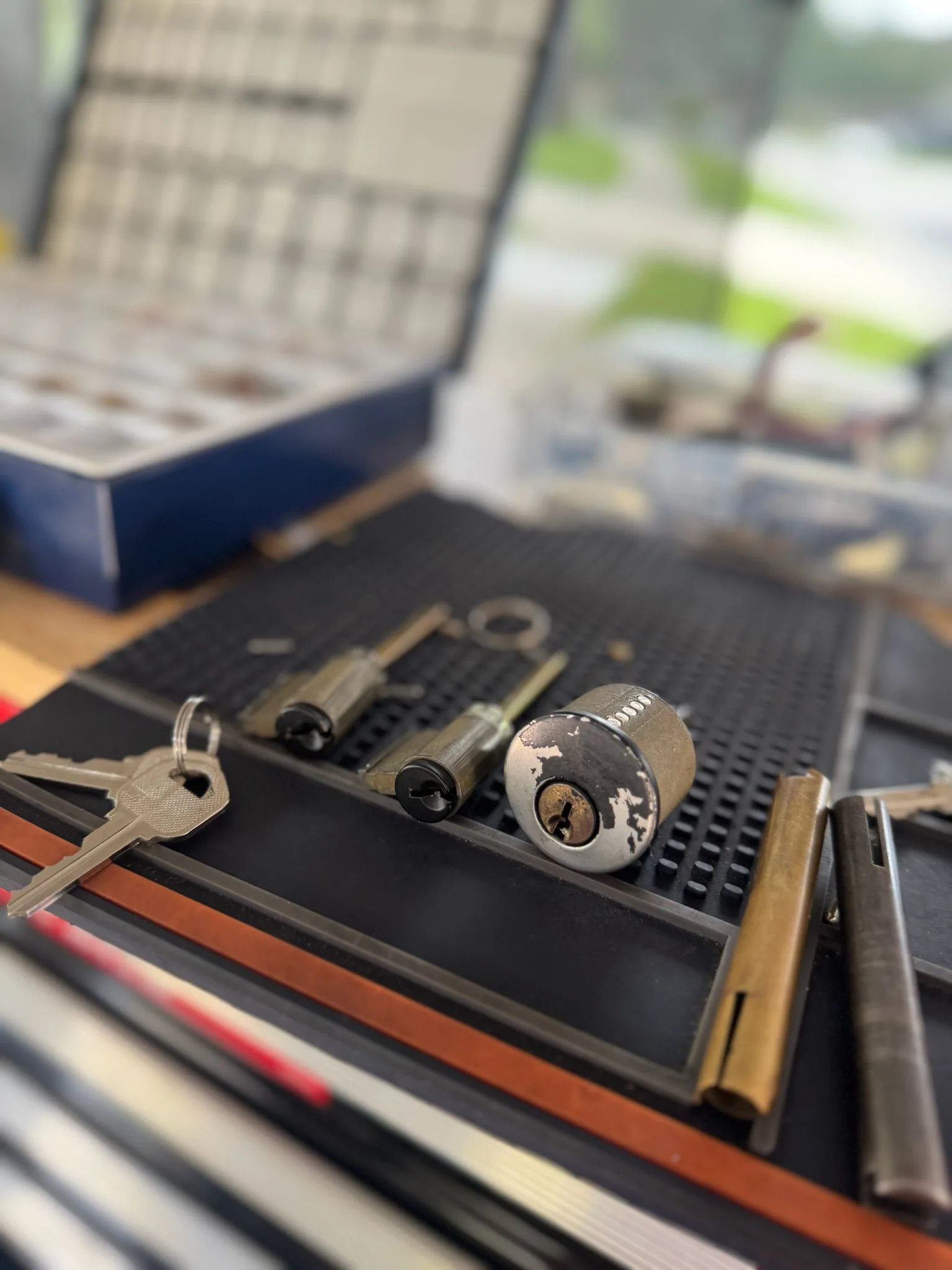 Locksmith Services by Local Locksmith Pros LLC, featuring a close-up of lock cylinders, keys, and pinning tools on a workbench for re-keying and repair.