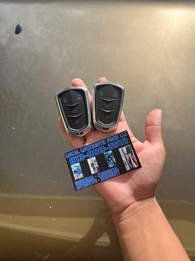 A technician from Local Locksmith Pros LLC holding two new smart key fobs and a business card, showcasing a successful Car Key Replacement service.