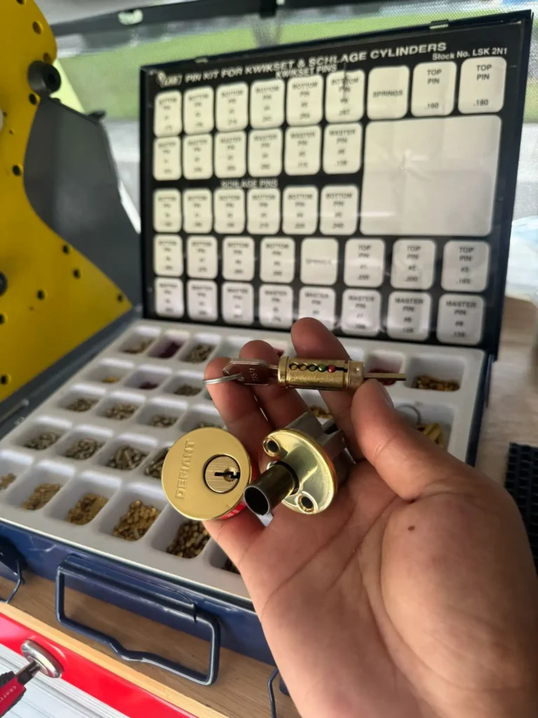 Professional Locksmith Services by Local Locksmith Pros LLC, showcasing a technician's hand holding a lock cylinder and a re-pinned core in front of a master pinning kit.
